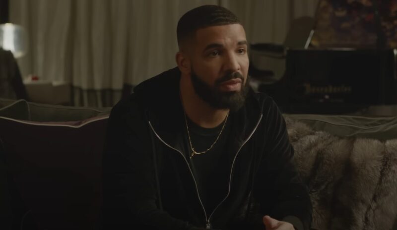 Drake, seated in a plush, dimly lit room