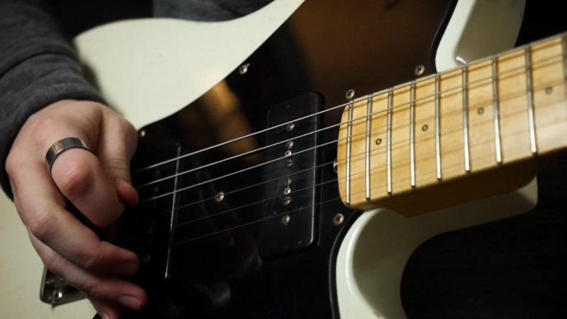 A Close-Up of A Guitarist's Hand Playing an Electric Guitar