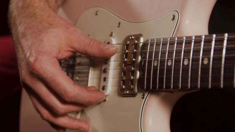 A Guitarist Tuning an Electric Guitar, Adjusting the Strings While Playing