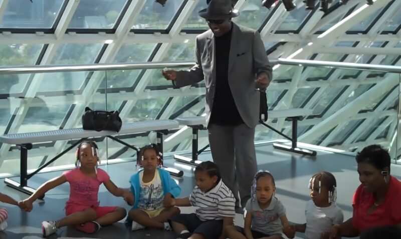 Walter Williams smiling while speaking with children