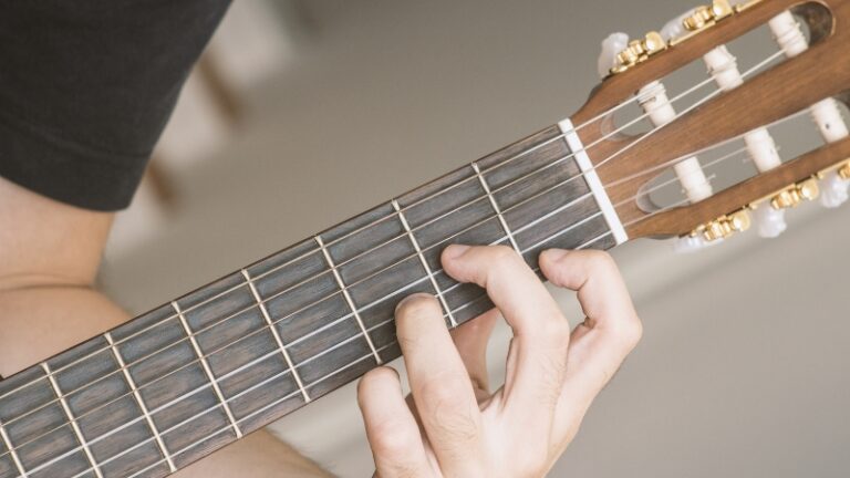 A Person Playing a Guitar Chord in D Minor on The Fretboard