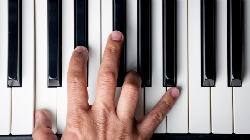 Hand Pressing a Key on A Piano, Illustrating the C Minor Scale