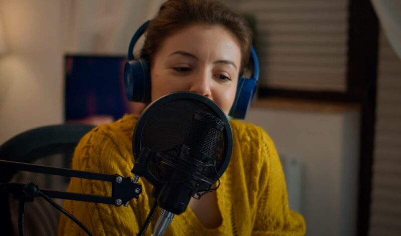 A podcast host, sharing stories and insights, in a home recording space