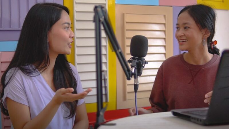 Two women engaged in a lively podcast discussion