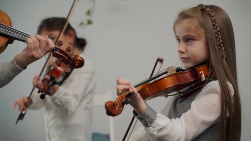 Young children play the violin during a music lesson, focused on learning technique and rhythm