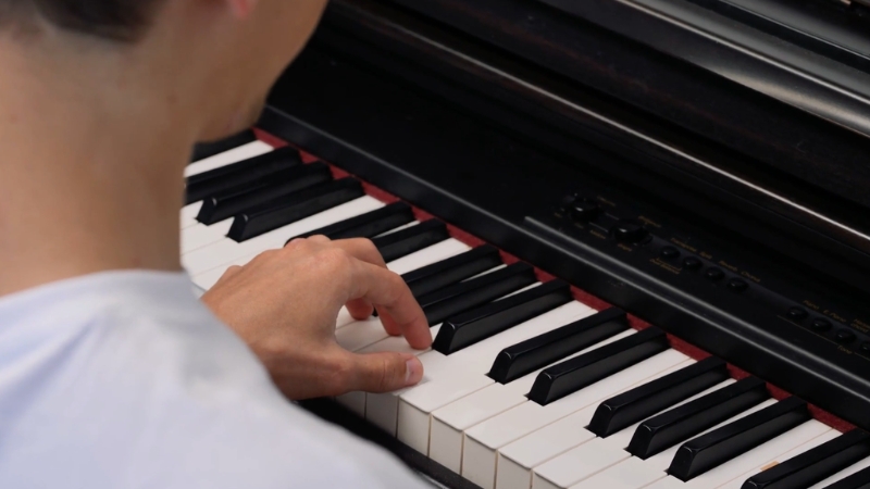 A person practices on a digital piano, focusing on hand placement and finger movement