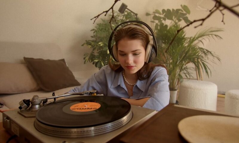 A young woman engrossed in a vintage record player, headphones on, lost in the music