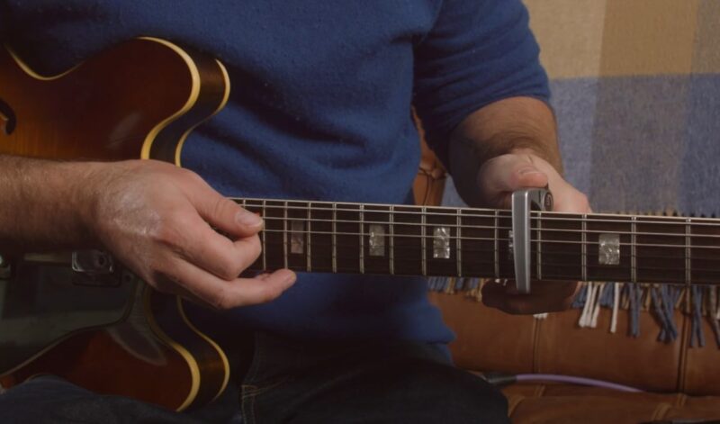Close up view of a guitar player adjusting capo