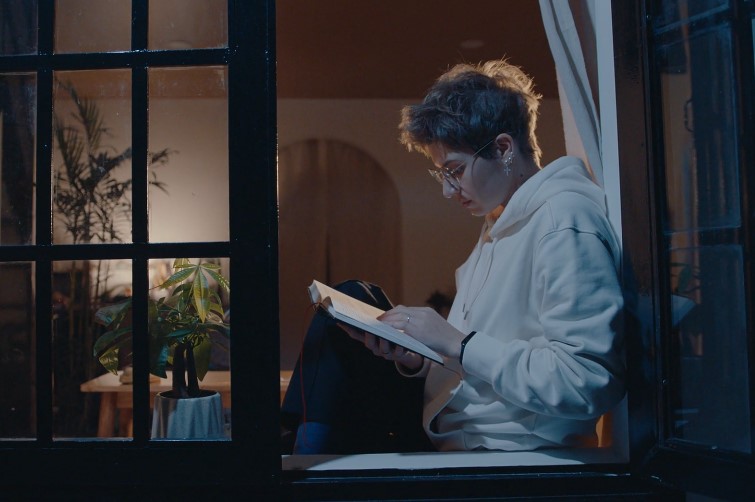 A person engrossed in a book by the window, bathed in the soft glow of the evening