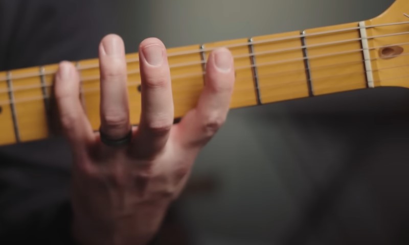 A person playing an electric guitar, skillfully using their fingers on the strings
