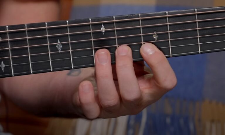 Fretting hand positioning on a guitar neck, showing precise finger placement on steel strings