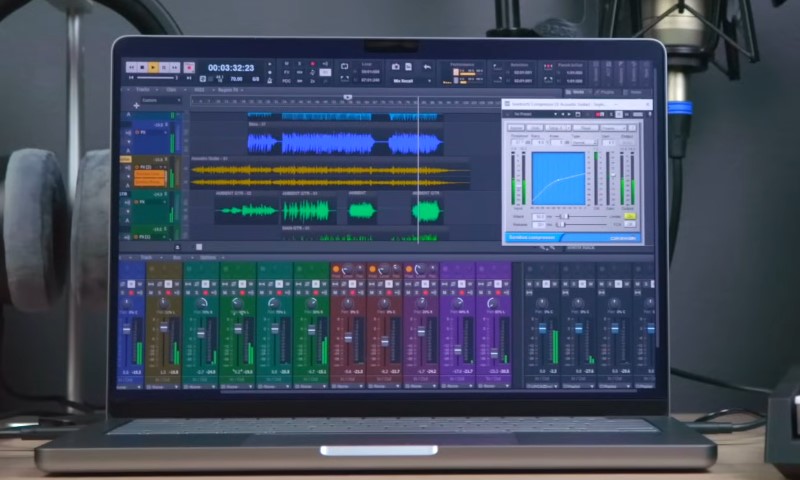 A laptop displaying music software with various audio tracks and controls visible on the screen