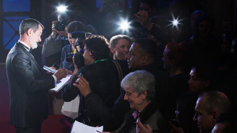A celebrity manager coordinating media interactions and managing client exposure during a red-carpet event