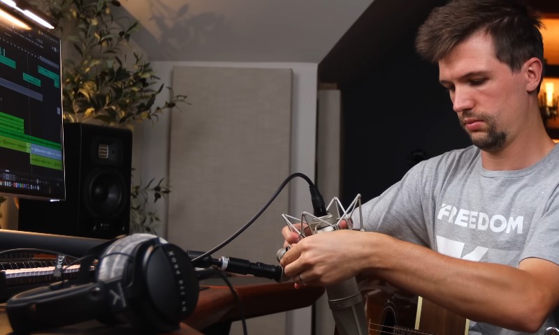 A man adjusts a microphone while working in a professional recording studio
