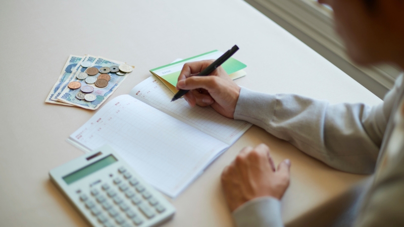 A celebrity manager reviewing finances and schedules with a calculator and notebook on a desk