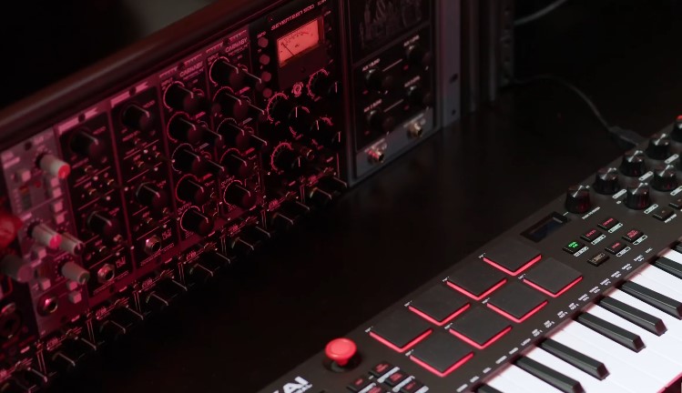 Close-up of a keyboard alongside various electronic music equipment
