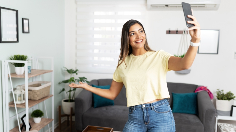 An influencer recording content on a smartphone in a bright, modern living room