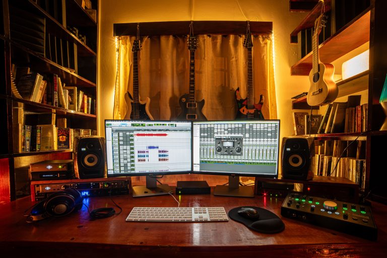A well-equipped home music studio with guitars, monitors, and recording software